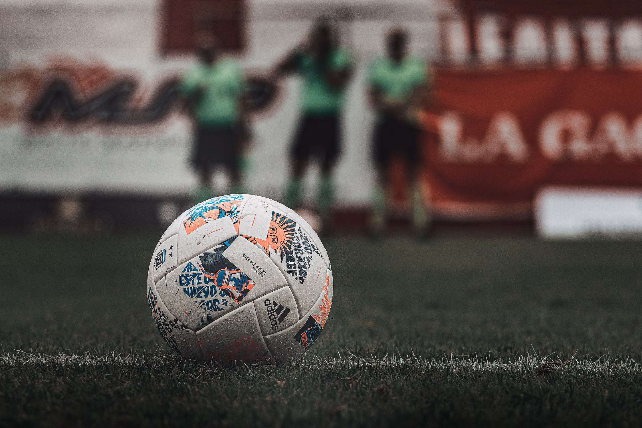 Fußball auf dem Rasen, Spieler im Hintergrund.